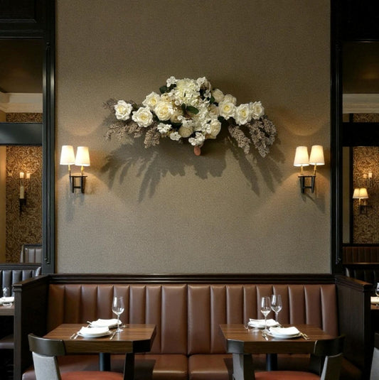 Decorative floral arrangement on a wall above a restaurant booth with tables and chairs.