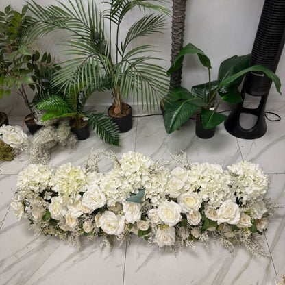 Floral arrangement on a marble floor with plants in the background