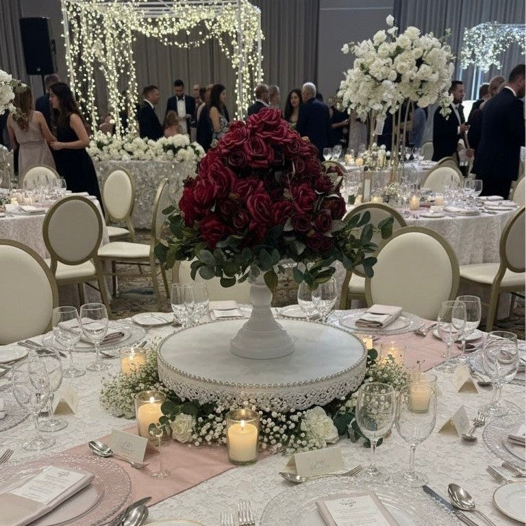 Decorated banquet hall with tables set for a formal event, featuring floral centerpieces and elegant table settings.