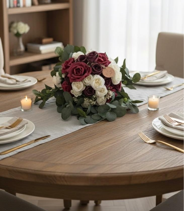 Dining table set with a floral centerpiece, candles, and cutlery.