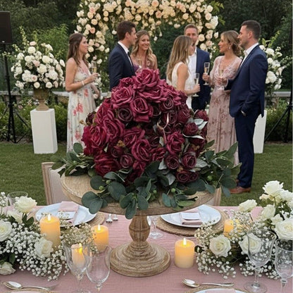 Outdoor wedding reception with guests, floral arrangements, and a large floral centerpiece.
