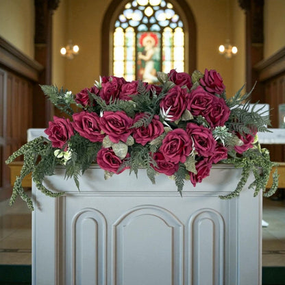 Decorative floral arrangement on a pulpit with stained glass window in the background