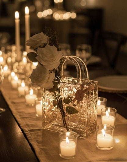 Glass handbag with white roses on a table surrounded by candles in a dimly lit setting