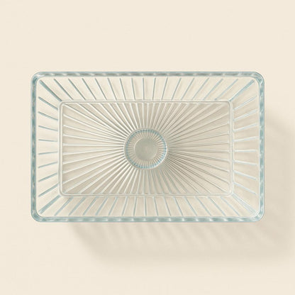 Clear glass rectangular bowl with starburst pattern on a beige background