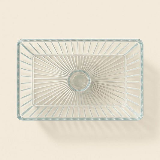 Clear glass rectangular bowl with starburst pattern on a beige background