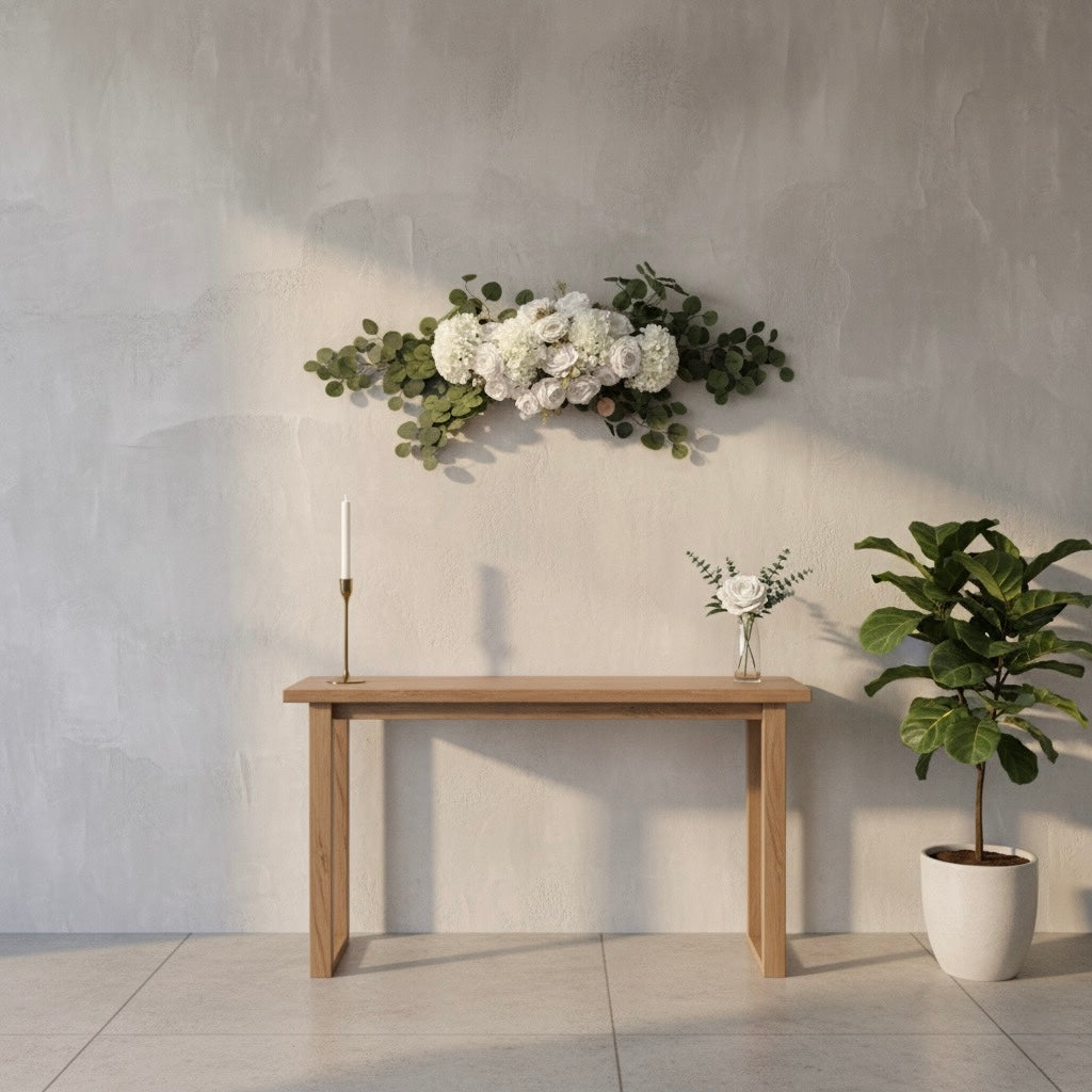 Wooden table with decorative flowers and a plant against a gray wall.