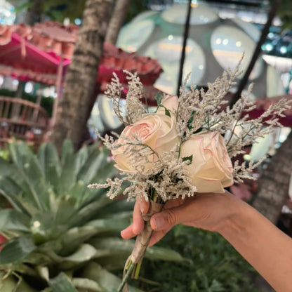 Hand holding a bouquet of flowers with a blurred background