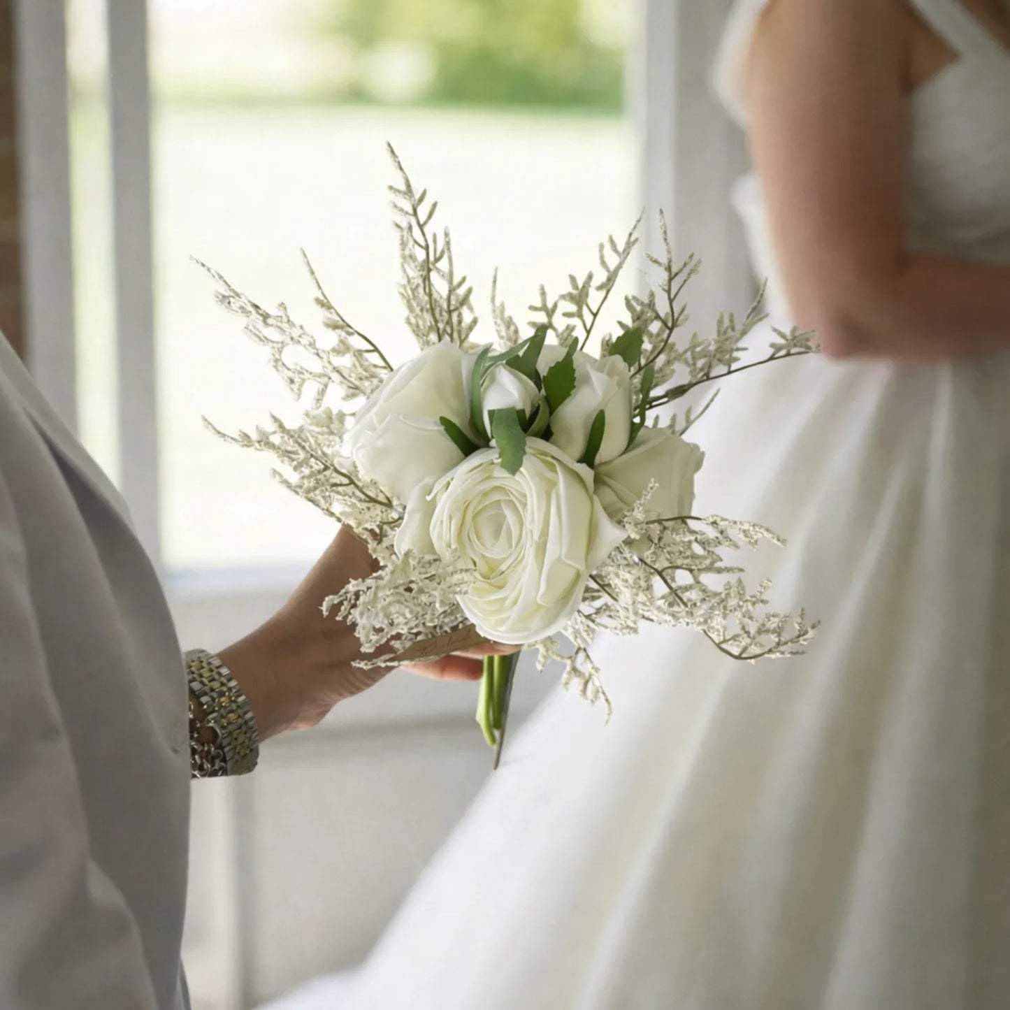 Bouquet of white roses held by a person in a wedding setting