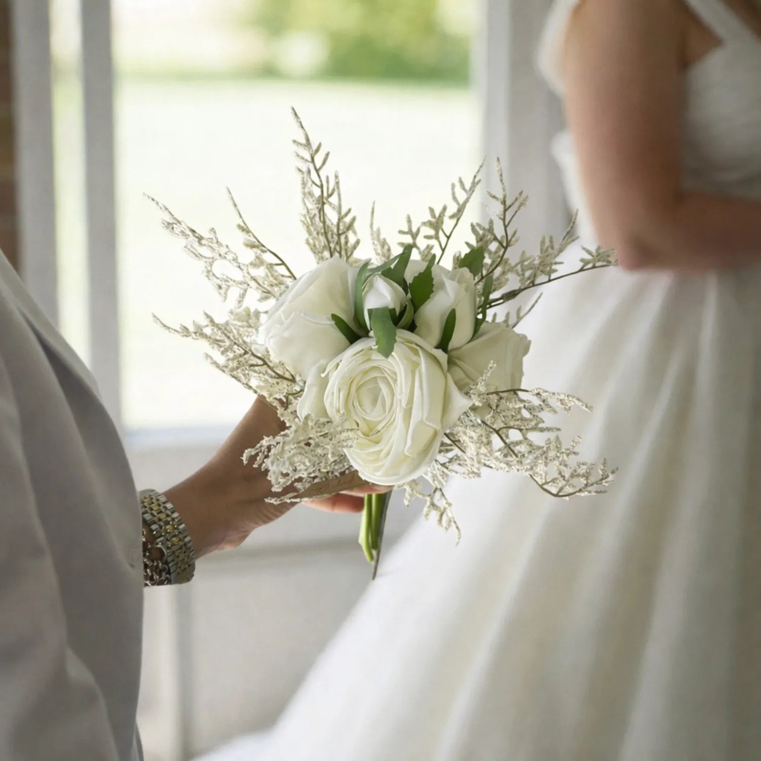 Bouquet of white roses held by a person in a wedding setting