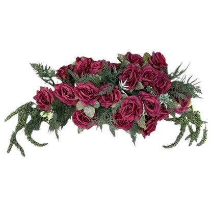 Artificial flower arrangement with red roses and greenery on a white background