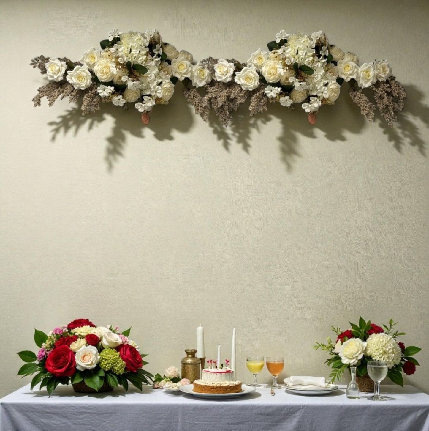 Decorative floral arrangement above a table set with a cake and drinks.