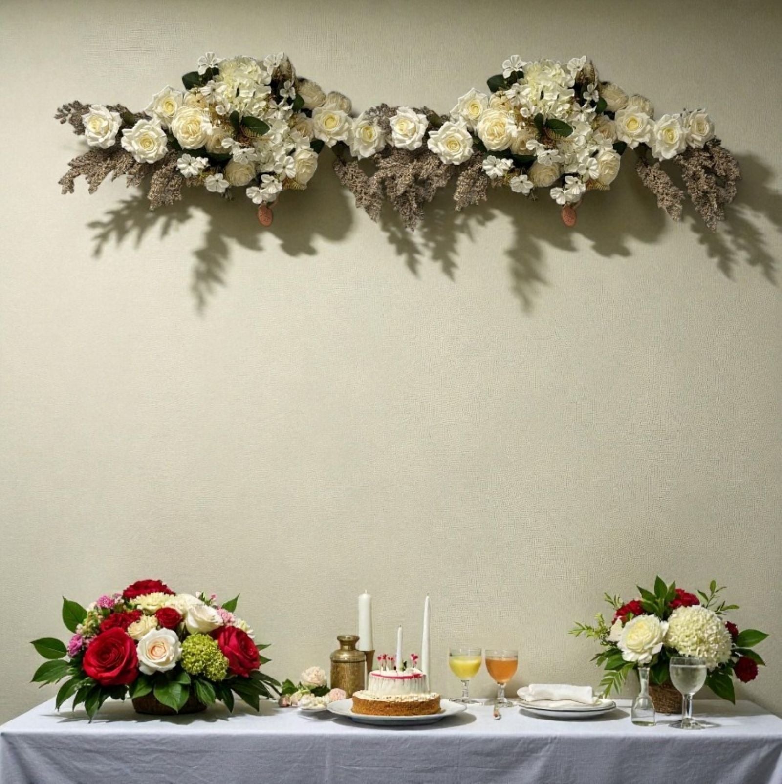 Decorative floral arrangement above a table set with a cake and drinks.