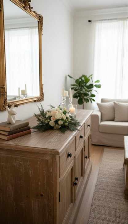 Living room with wooden sideboard, floral arrangement, and sofa.