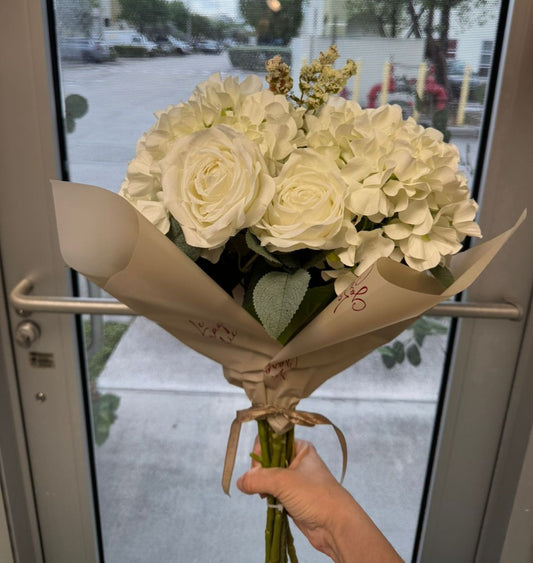 Bouquet of white flowers held in front of a glass door
