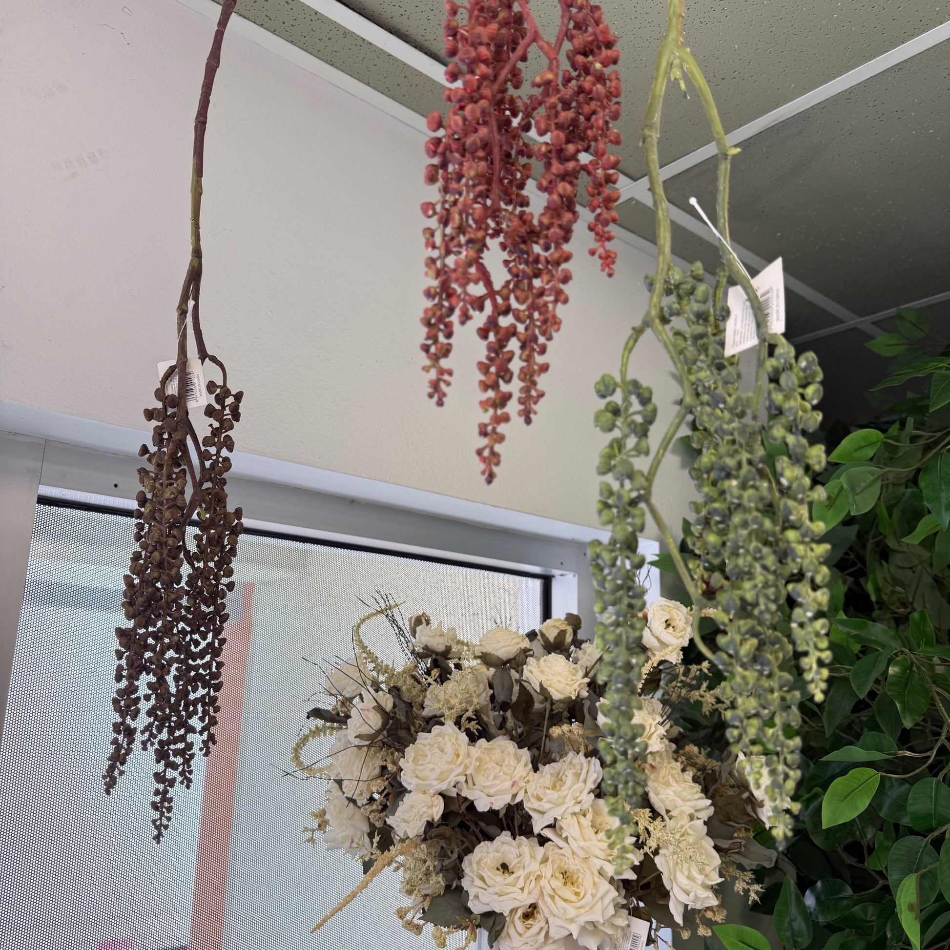 Decorative hanging plants and flowers against a neutral wall.