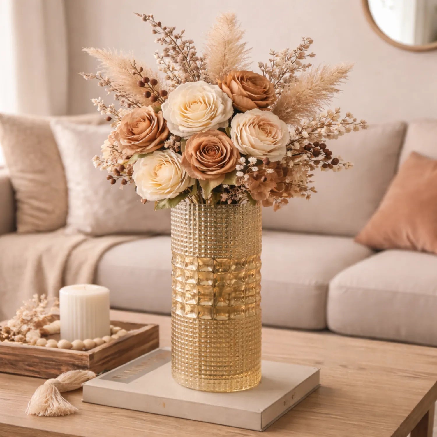 Decorative floral arrangement in a amber vase on a coffee table with a neutral-colored sofa in the background.
