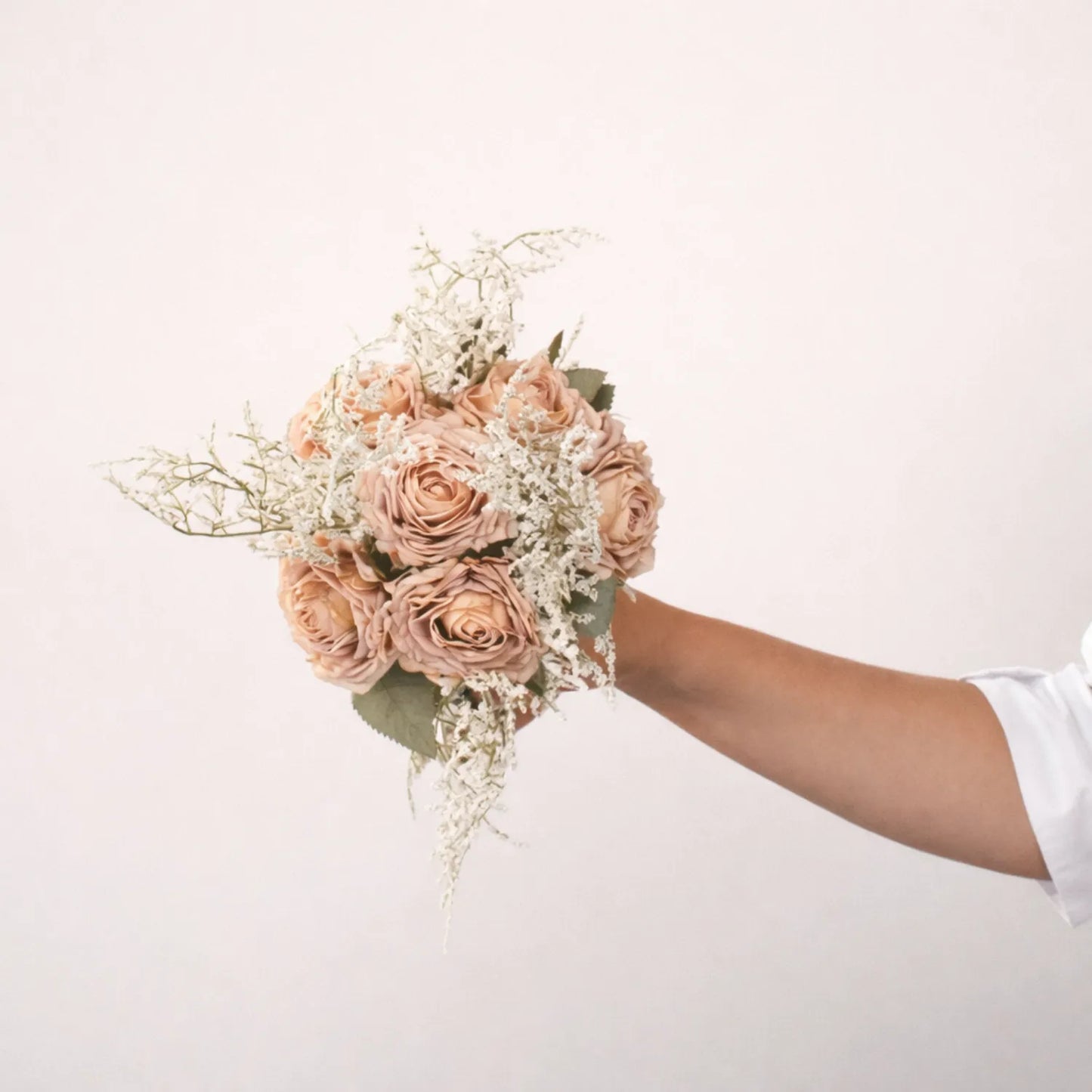 Bouquet of pink roses held by a person against a white background