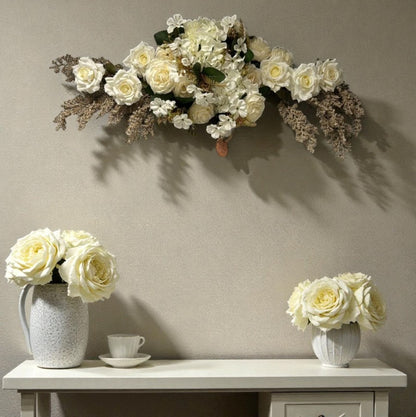 Floral arrangement on a wall above a table with flowers in vases.