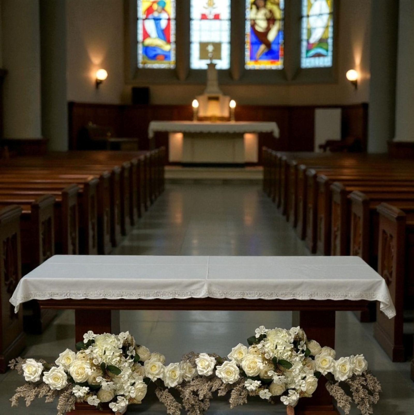 Nave of a church with pews, altar, and stained glass windows.