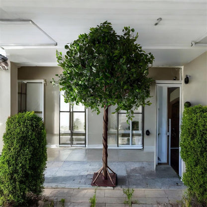 Artificial tree in a decorative pot on a patio with a modern building in the background