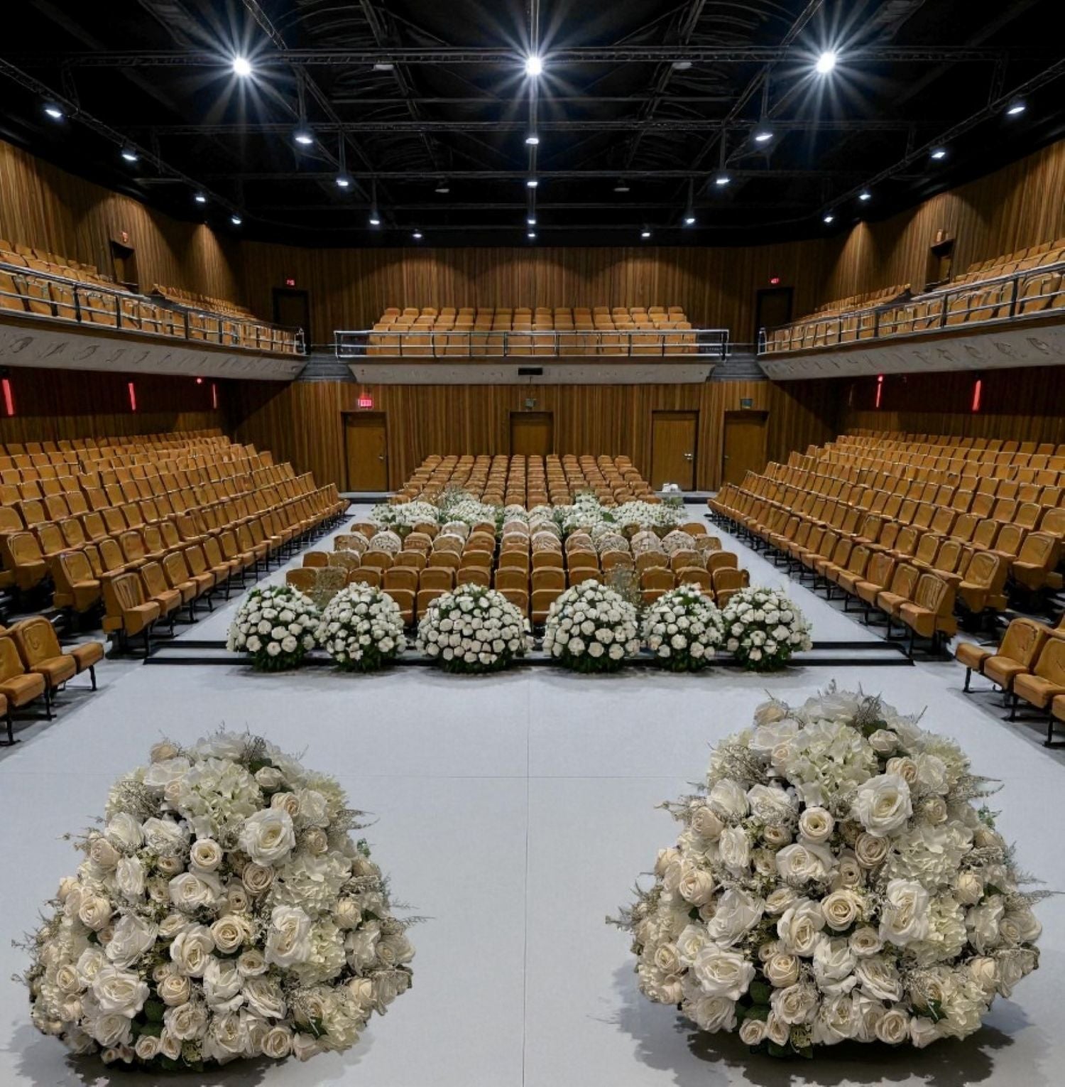 Large auditorium with rows of chairs and decorative flower arrangements on the floor.