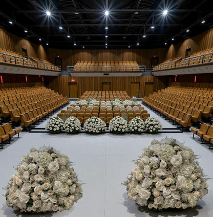 Large auditorium with rows of chairs and decorative flower arrangements on the floor.