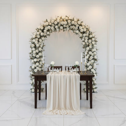 Decorative floral arch with a table set for a romantic dinner in a white room.