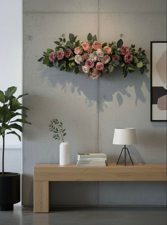 Floral arrangement above a wooden console table with decor items in a room.