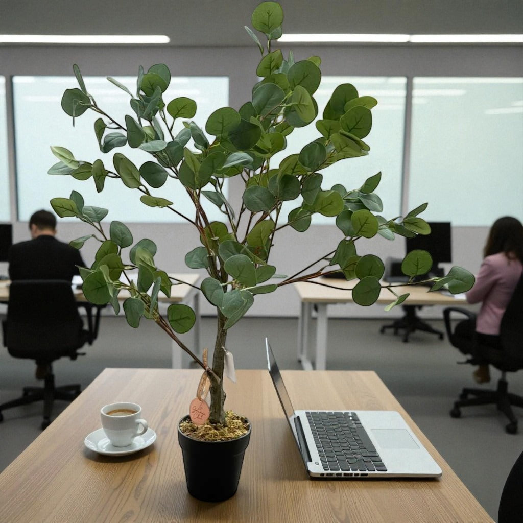 Laptop on a desk with a potted plant and coffee cup in an office setting