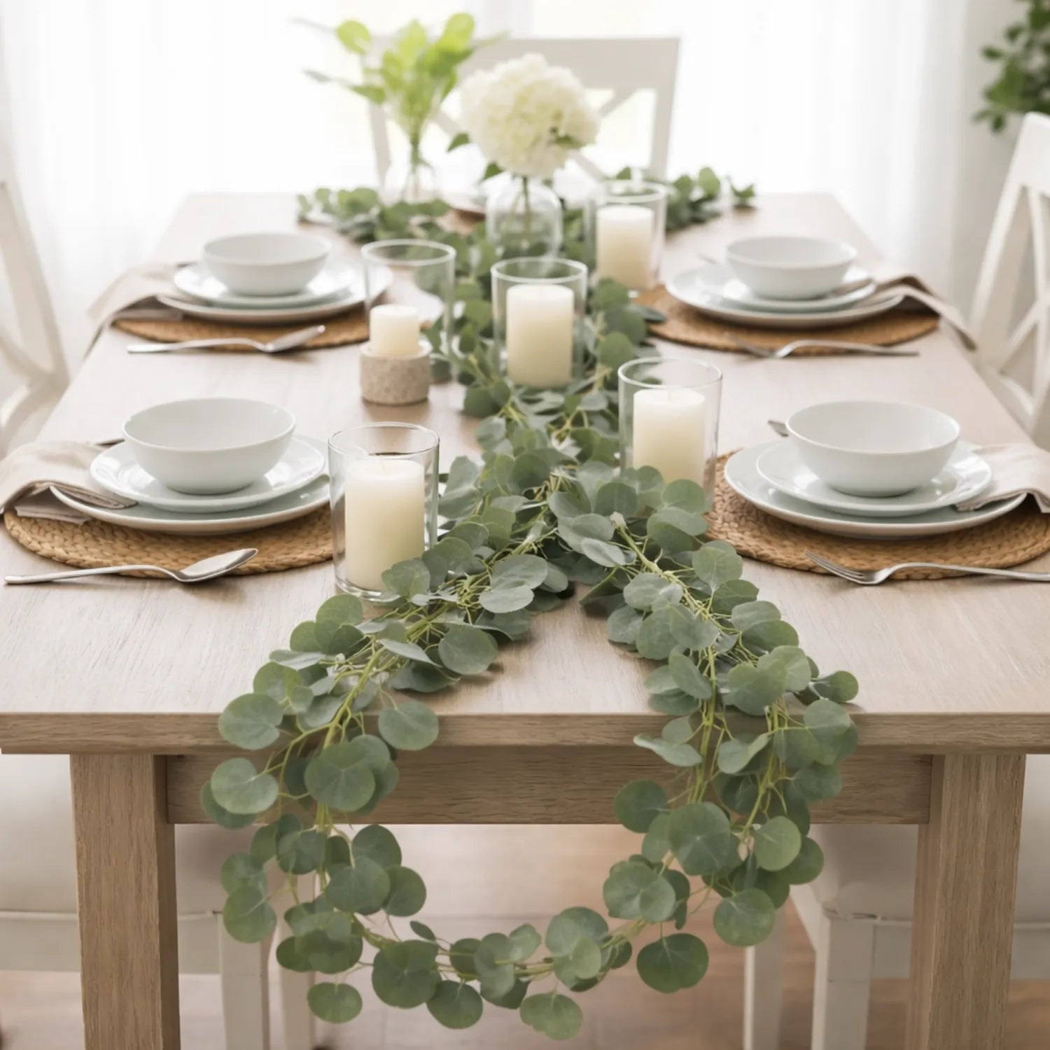 Elegant table setting with greenery and candles on a wooden table.