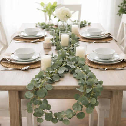 Elegant table setting with greenery and candles on a wooden table.