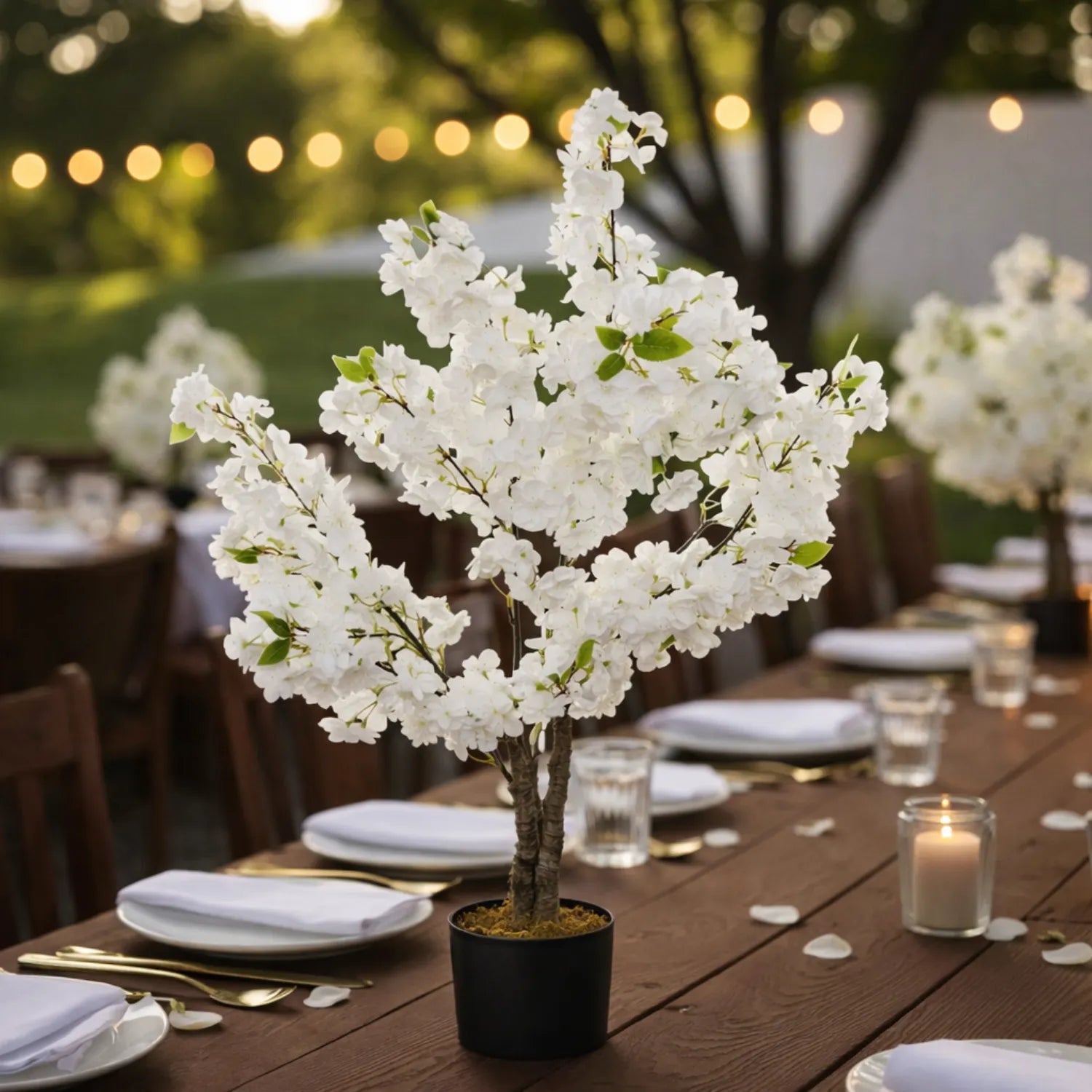 Decorative white floral arrangement on a wooden table with setting in an outdoor garden.