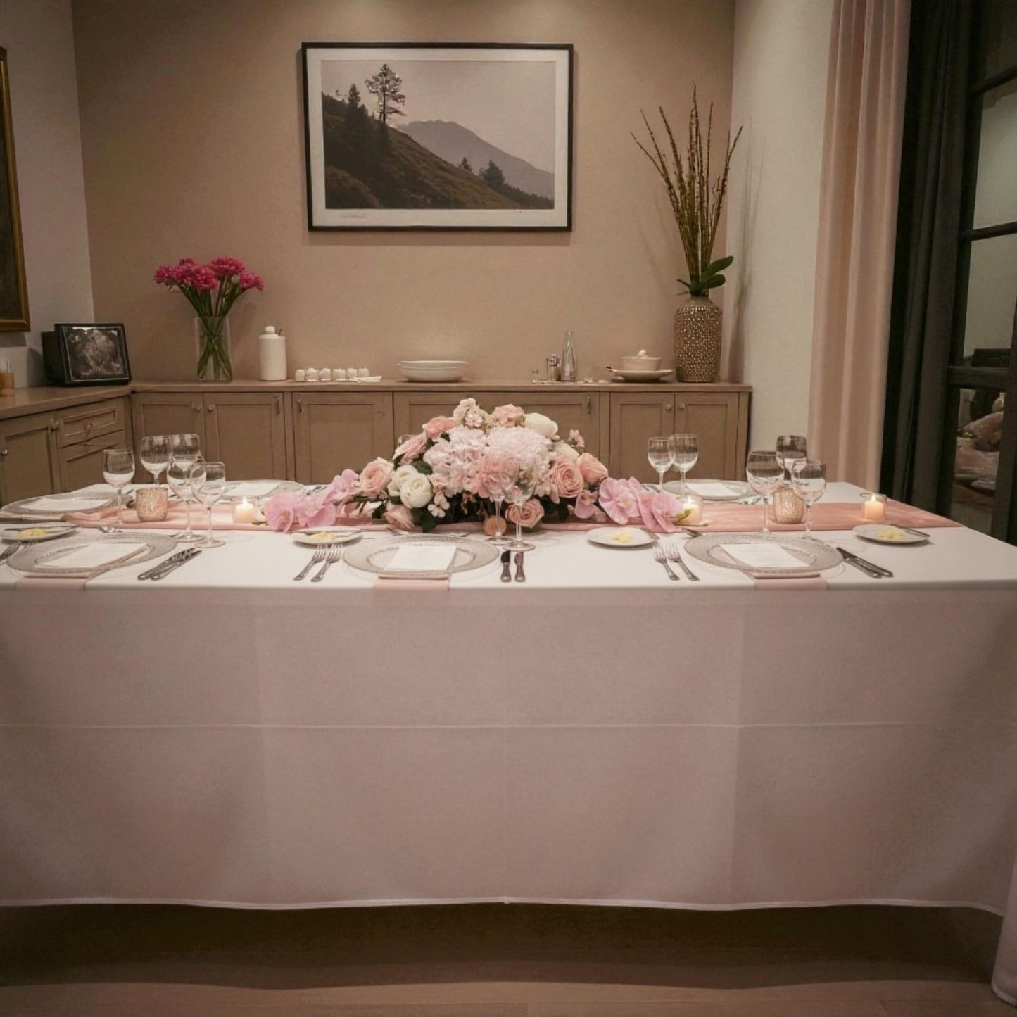Dining room with a table set for a meal, featuring flowers and candles.