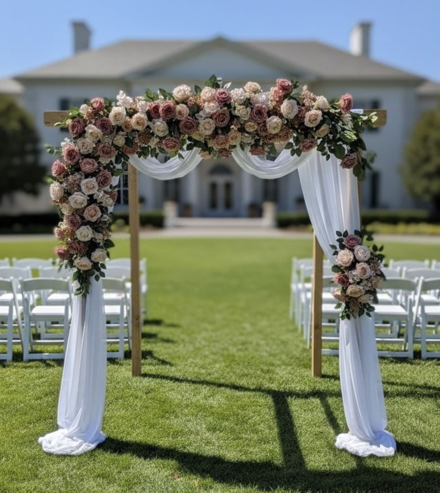 Decorative floral arch with white drapes in front of a building