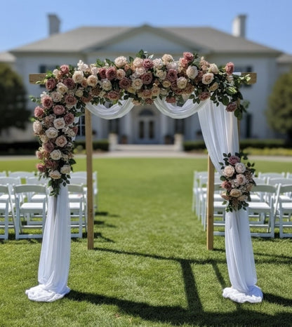 Decorative floral arch with white drapes in front of a building