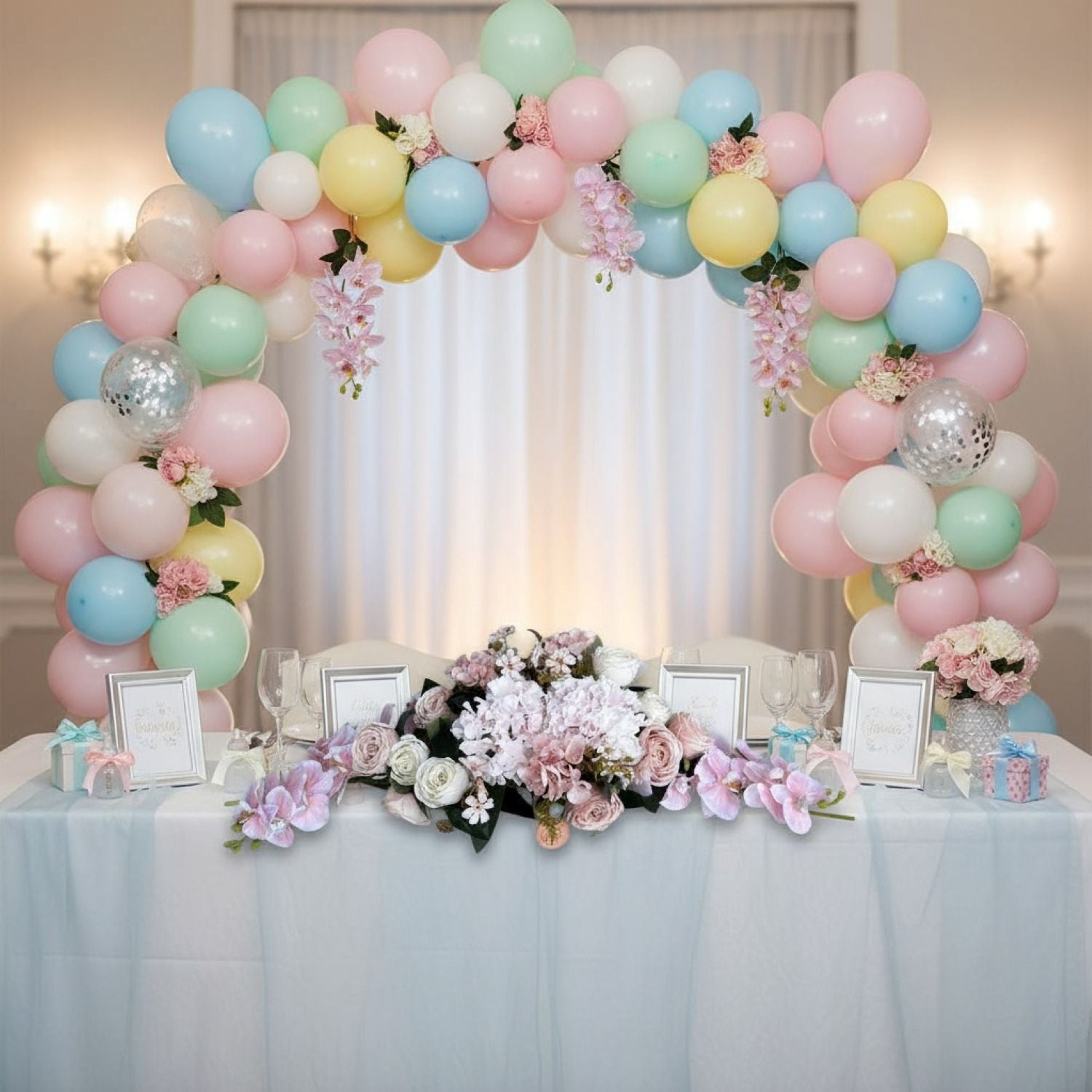 Decorative balloon arch with flowers over a table set for a celebration.