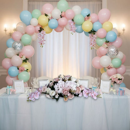 Decorative balloon arch with flowers over a table set for a celebration.