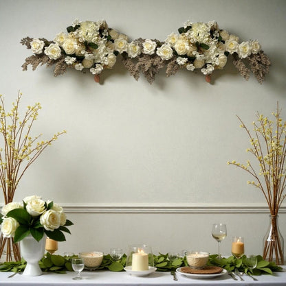 Decorative floral arrangement on a wall above a table set with candles and glasses.