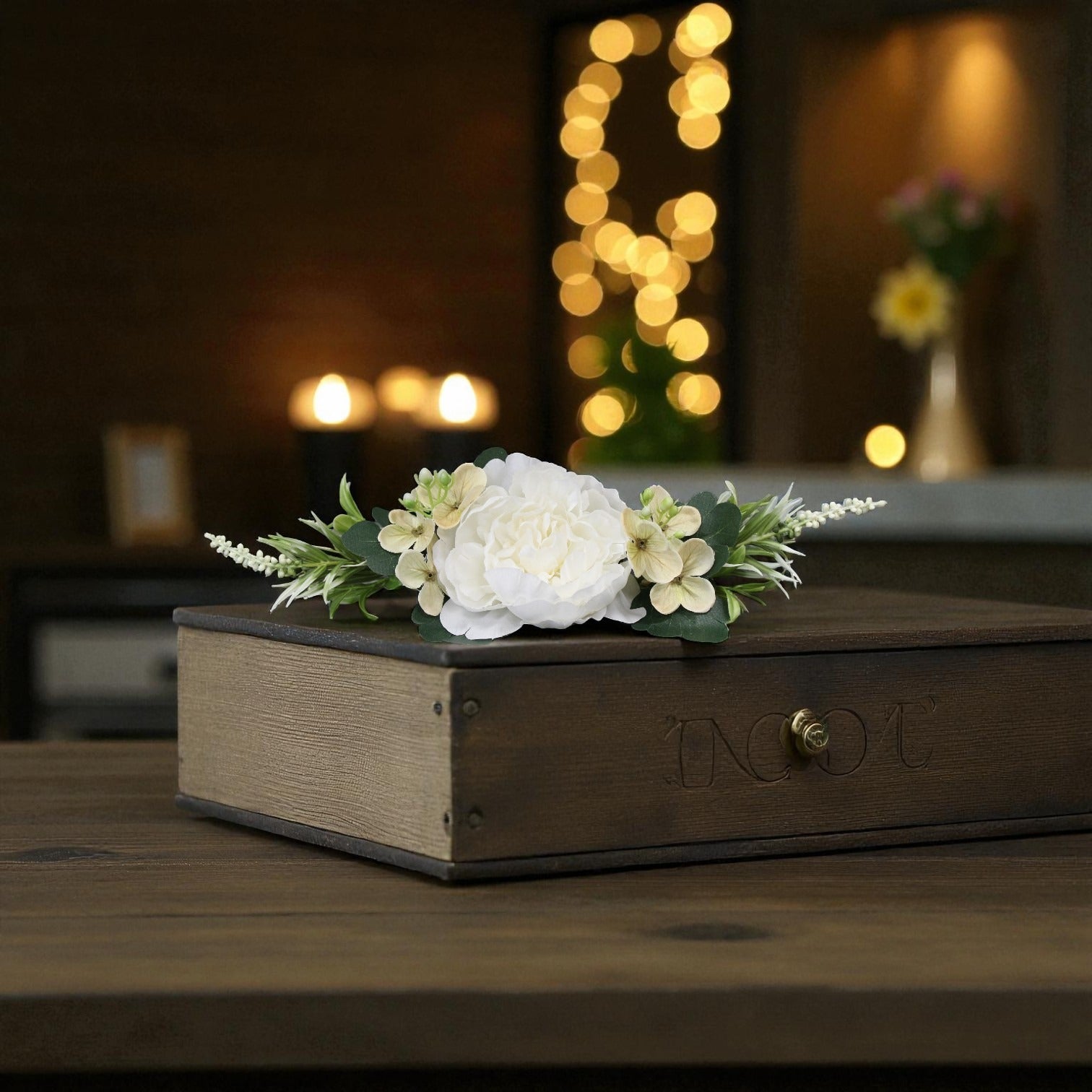 Wooden box with white flowers on a wooden surface with blurred lights in the background