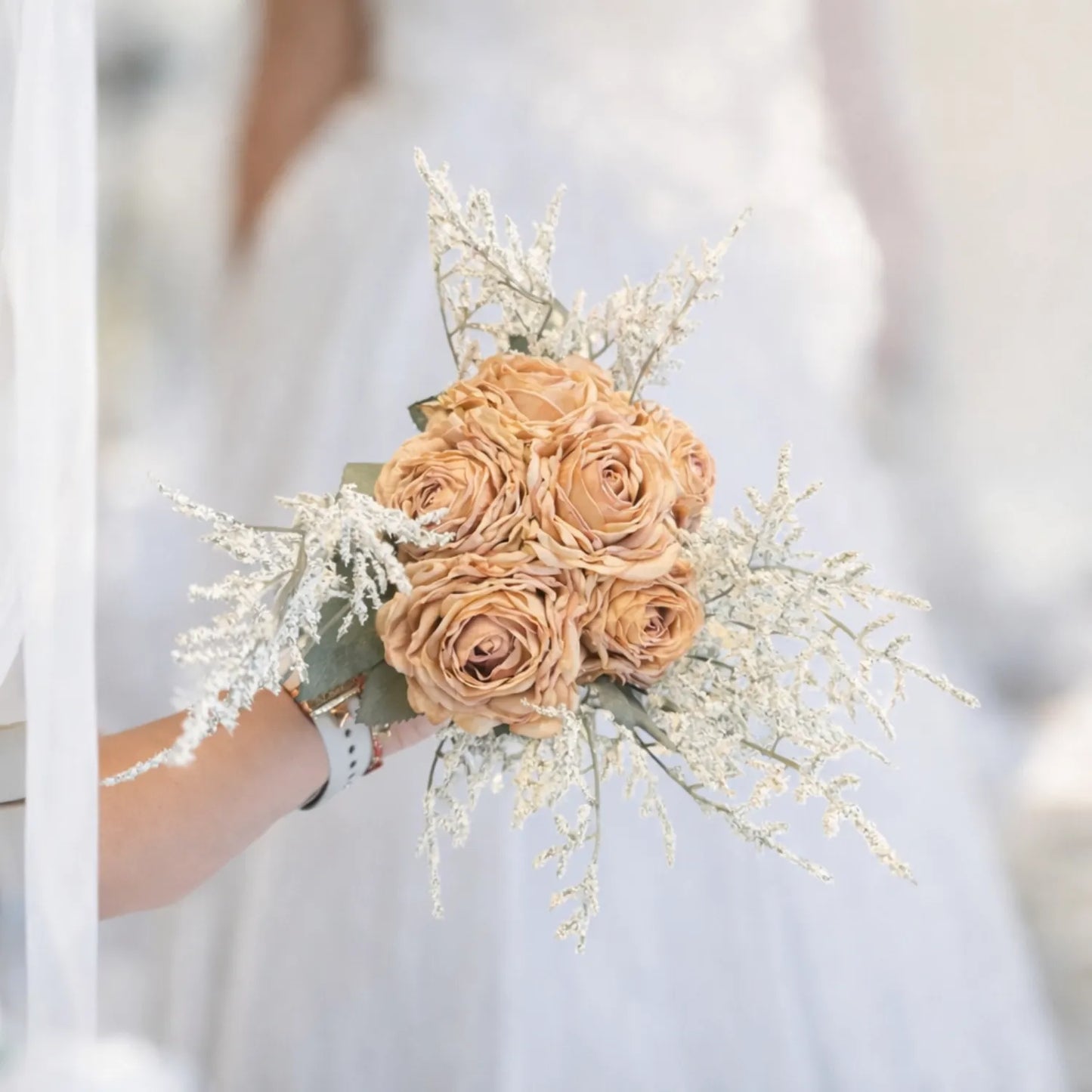 Bouquet of peach-colored roses held by a person against a blurred white background