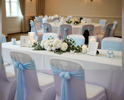 Decorated event room with tables, chairs, and floral centerpieces.