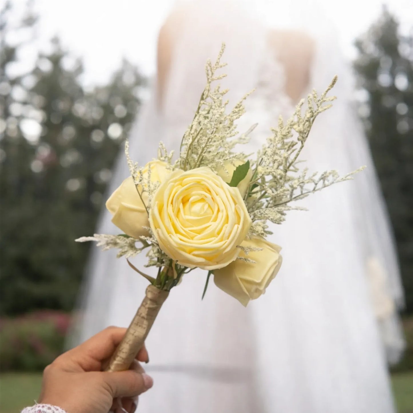 Bouquet of yellow flowers held by a hand with a blurred background